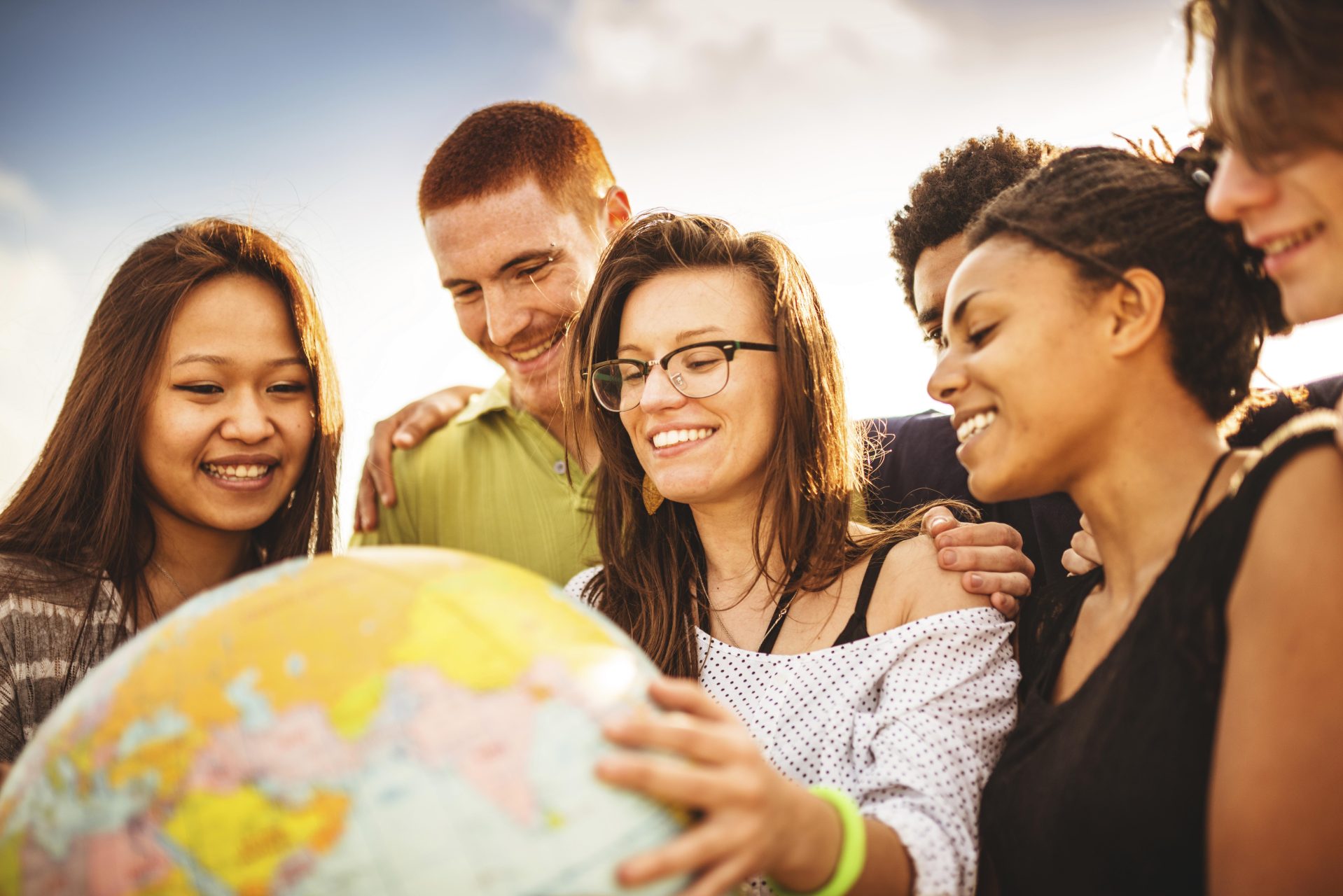 Students smiling and holding globe
